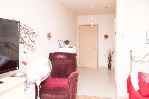 Bedroom sitting area with a red recliner, television, fan and floral wall decorations