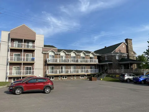 Residence with white balconies, a stone-clad entrance and cars in the paved forecourt