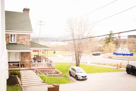 Residence entrance with steps, a covered porch and cars parked nearby