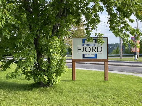 Residence sign beside a lawn, leafy tree and road