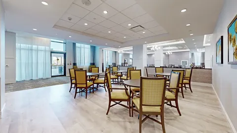 Room with tables, chairs, a kitchen counter and white cupboards
