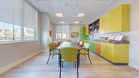 Art room with a table, easel, yellow cupboards and a sink