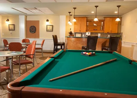 Games room with a billiards table, card tables and kitchen counter.