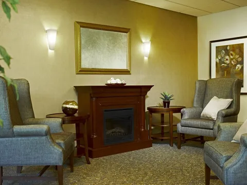 Seating area with grey armchairs, a fireplace and a wall mirror
