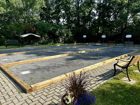 Outdoor game courts beside benches, a paved path and trees