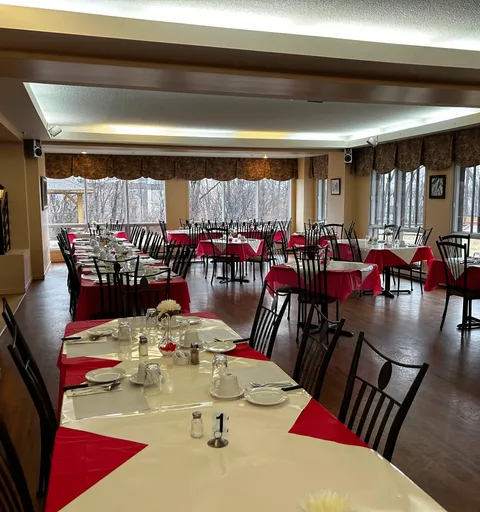 Dining room with set tables, red and white tablecloths and large windows