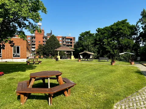 Lawn with a picnic table, trees, a gazebo and a residence in the background