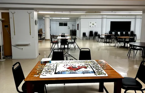 Activity room with tables, chairs, a shuffleboard court and a jigsaw puzzle