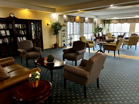 Room with armchairs, bookcases, plants and large windows