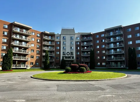 Residence exterior with rows of balconies, shrubs and a circular drive