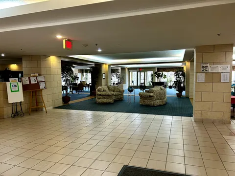 Entrance lobby with tiled flooring, a round table, plants and landscape art