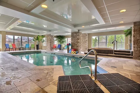 Indoor swimming pool with tiled surroundings, coloured chairs and broad windows