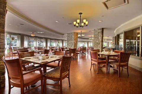 Dining room with set tables, wooden chairs, stone columns and broad windows