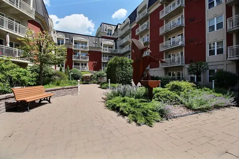 Residence wings around a planted courtyard with a bench and paved paths