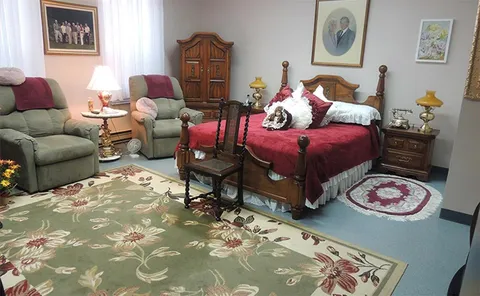 Furnished room with a bed, armchairs, rug and side tables.