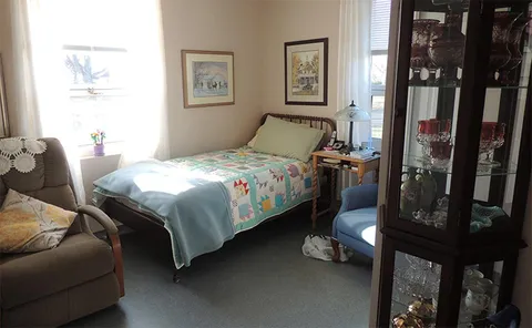 Bedroom with a single bed, armchair and window.