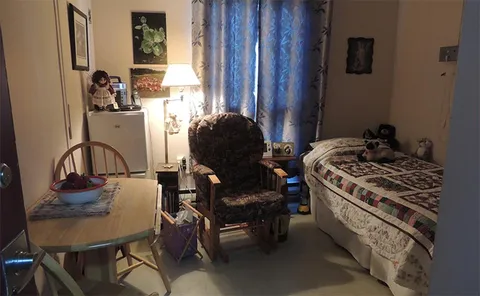 Furnished room with a single bed, armchair and side table.