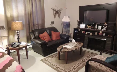 Room sitting area with a sofa, television and coffee table.