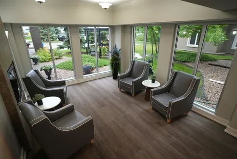 Room with four armchairs, round tables and large windows