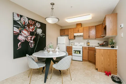 Kitchen and dining area with wooden cupboards and floral wall art