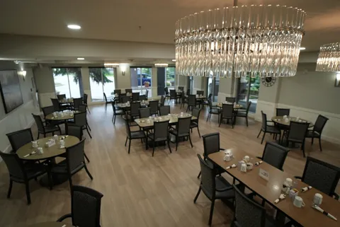 Dining room with dark chairs, set tables and a chandelier