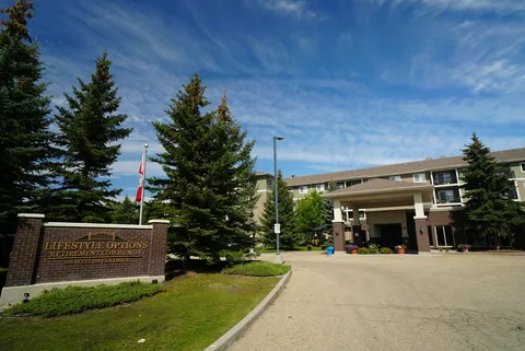 Residence entrance with a driveway, trees and a stone sign