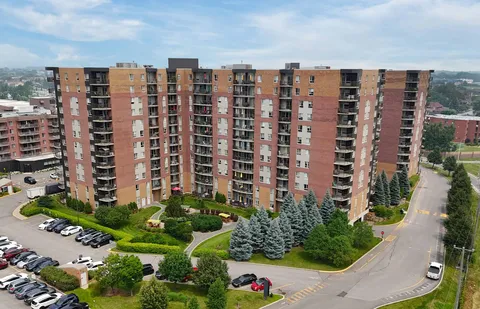 Aerial view of a brick residence building with balconies, paths and gardens.