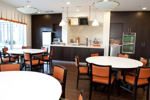 Activity kitchen with round tables, chairs, ovens and a counter.