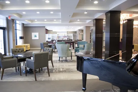 Lobby lounge with armchairs, tables and a grand piano.