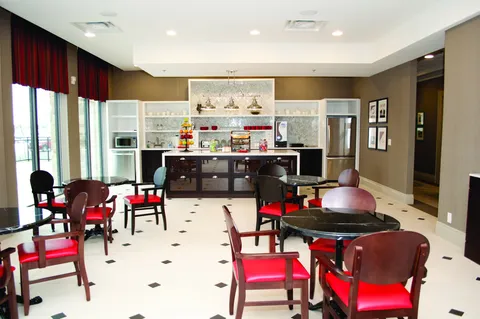 Cafe seating area with round tables, red chairs and a service counter.