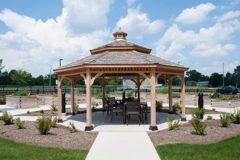 Garden gazebo with tables and chairs beside raised planting beds.