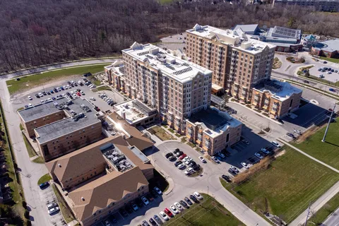 Aerial view of residence buildings, parking areas and nearby woodland