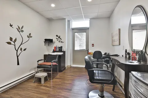 Hair salon with black chairs, an oval mirror and a wash basin