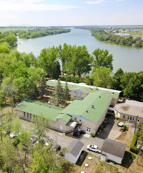 Aerial view of a green-roofed building, trees and a river