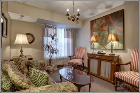 Sitting room with a sofa, armchairs, coffee table and window.