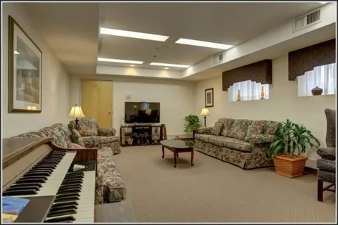 Lounge with sofas, armchairs, a television and piano.