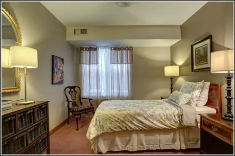Bedroom with a bed, desk, armchair and window.