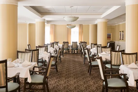 Dining room with set tables, columns and upholstered chairs.