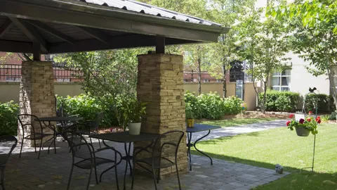 Garden courtyard with a covered patio, tables and chairs.