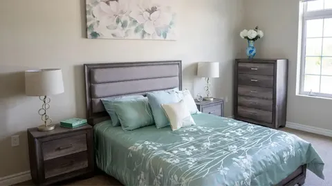 Bedroom with a bed, dresser and bedside tables.