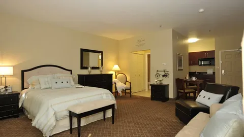 Furnished studio suite with a bed, kitchenette and sitting area.