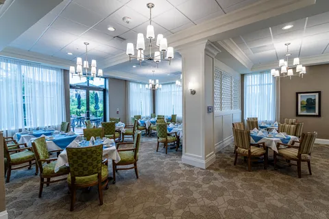Dining room with set tables, green upholstered chairs and chandeliers