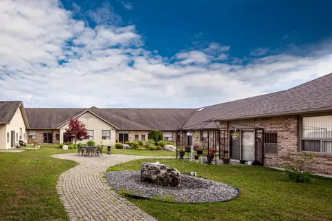 Residence building around a lawn with curved paths and patio seating