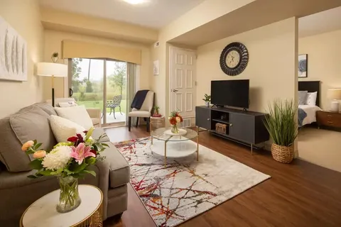 Sitting area with a sofa, television, coffee table and balcony door