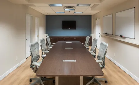 Meeting room with long table and wall mounted screen