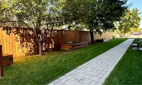 Paved garden path with benches and a wooden fence