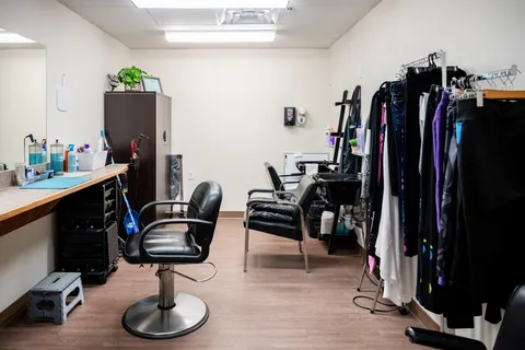 Salon with mirrors, styling chairs, counters and a rack of clothing