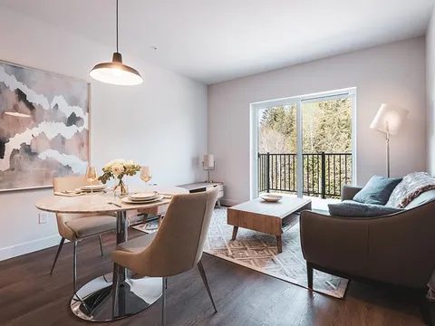 Open room with a sofa, dining table and sliding door to a balcony