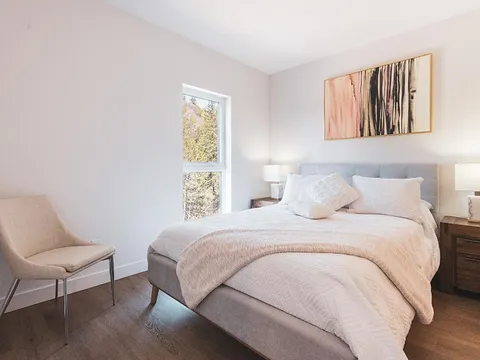 Bedroom with a bed, upholstered chair and abstract artwork