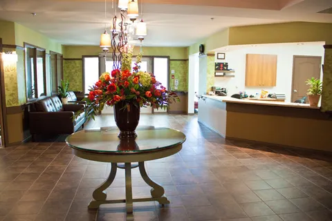 Lobby with a reception counter, seating and flowers on a round table.